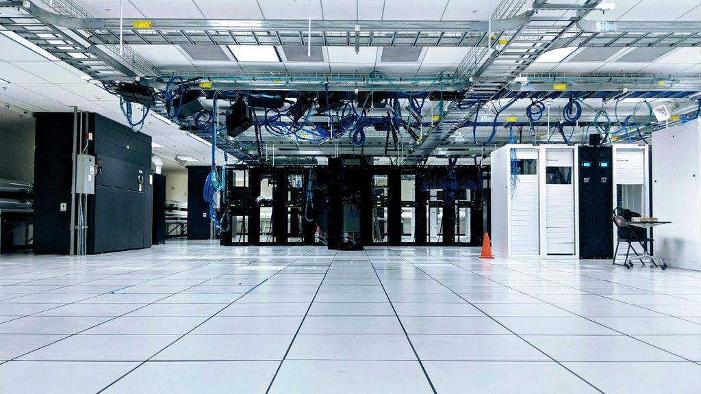 Server room with rows of equipment cabinets and overhead cable trays